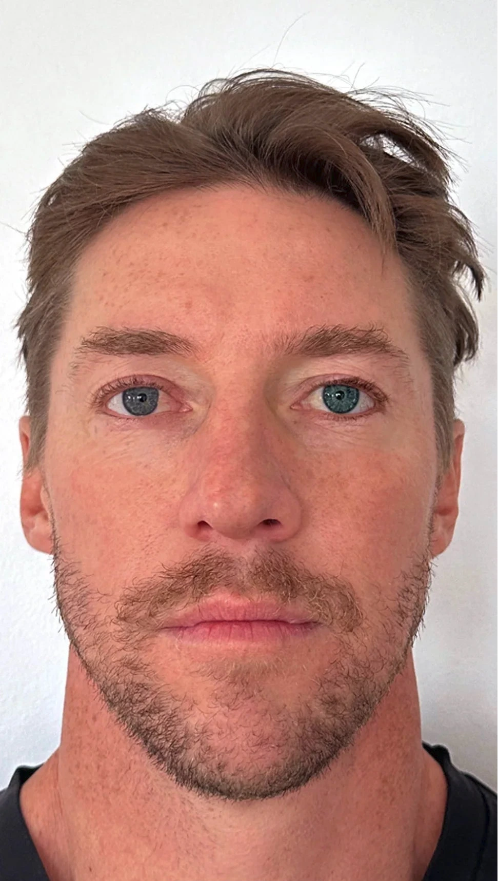 Close-up of a person with short hair and a beard against a white background